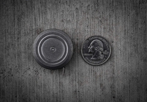 Ultra Tiny Titanium Ti Tape Retractable Mini Tape Measure With 3 Feet Range next to a quarter on concrete surface