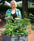 Woman tending plants in City Picker Raised Bed Grow Box With Self Watering System And Improved Aeration Mobile Garden On Patio