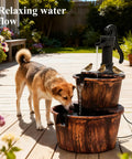 Dog drinking from Rustic Two Tier Barrel Waterfall Fountain For Backyard Patio And Garden Bronze Finish 27 Inch Electric Water Feature With Pump Included Freestanding Floor Or Tabletop Decor Durable Polypropylene Construction For Yard Oasis