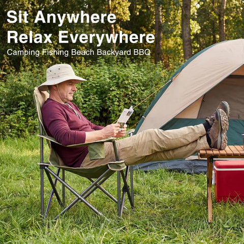 Man sitting in Foldable Camping Chair With Cup Holder, Non Slip Feet, Rock Solid, Heavy Duty Portable Collapsible Lawn Chair For Hiking, Beach And Sports, Thick 300D Oxford, 500 Lb Capacity, Green, reading at campsite.