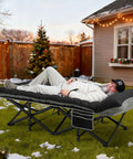 Man lounging on Extra Wide 32 Inch Camping Cot With Thick Mattress Holds Up To 600 Lbs, in a snowy backyard.