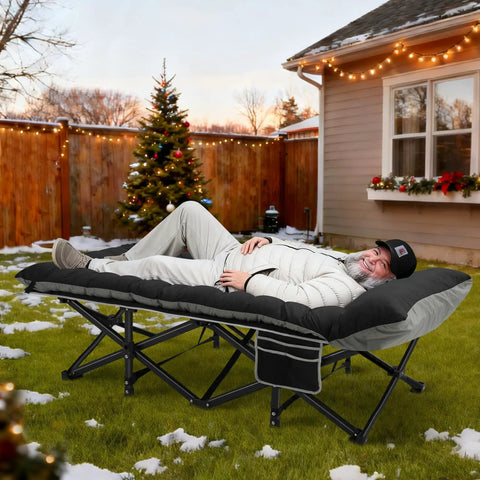 Man lounging on Extra Wide 32 Inch Camping Cot With Thick Mattress Holds Up To 600 Lbs, in a snowy backyard.