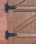 Wooden barn door with 6-Pack Heavy Duty 2 Inch T-Strap Hinges In Black Rustic Iron for outdoor sheds and fences.