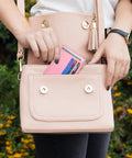 Woman placing slim RFID blocking wallet for women with front pocket card case, 6 card slots, ID window, chic pink, into purse