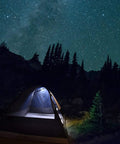 Illuminated tent under starry sky in forest showcasing Cordless LED Work Light Handy On The Go 350 Lumens for camping use.