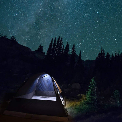 Illuminated tent under starry sky in forest showcasing Cordless LED Work Light Handy On The Go 350 Lumens for camping use.
