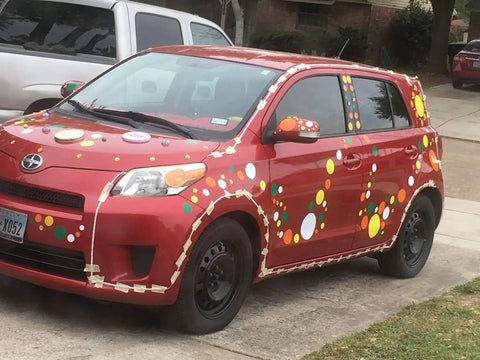 Red car decorated with colorful polka dots inspired by 63 White Polka Dot Wall Decals For Kids Rooms And Nurseries. Easy DIY decor.