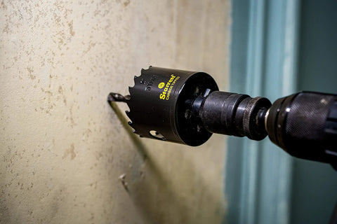 Carbide Tipped Hole Saw With Premium Finish For Wood PVC And Fiberglass Four And Three Quarters Inch Diameter One And Five Eighths Inch Cutting Depth Three Teeth Per Inch Built Tough For Real Pro Jobs CT434 drilling into wall