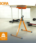 Tri Function Pedestal Roller Stand With Adjustable Height beside table saw, polished steel roller visible, in workshop