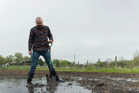Man using Short-Handle Digging Shovel With Heavy Duty Carbon Steel Build, Ergonomic No-Slip H-Grip, D Handle outdoors on wet soil.