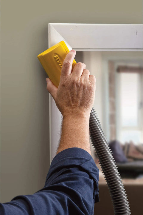 Hand using Lightweight Dust Free Sponge Sander Kit With Vacuum Hose And Two Sponges on doorframe edge.