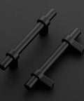 Two matte black cabinet pulls with square bases on a black surface, part of the 30 Pack Matte Black 5 Inch Cabinet Pulls With Square Base