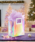 Holographic Gift Bags With Handles And Tissue Paper Sheets Included, Iridescent Transparent Reusable Purple Gift Bags, 8 By 7 By 4 Inch, shown by Christmas tree.