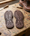 2 Pack Heavy Duty Rubber Sole Replacement Patches for Work Boots and Casual Sneakers on a workbench, cuttable dark brown rubber.