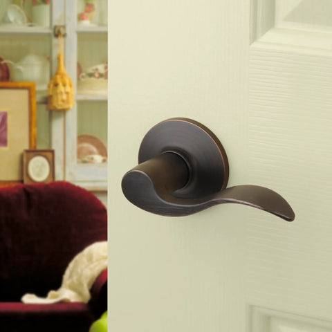 Heritage Lever Passage Set in Aged Oil Rubbed Bronze, installed on an interior door, view from side angle.