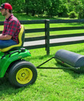 Tow Behind Lawn Roller 690 Lb Capacity With Easy Turn Plug, 36 Inch Wide Poly Drum attached to tractor on grass field.