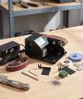 Compact Mini Electric Belt Sander With A Kickass Motor For Handheld Wood Sanding And Fast Metal Polishing Quick Rust Removal And Smooth DIY Finishes Built Like A Rock Solid Workhorse on a workbench.