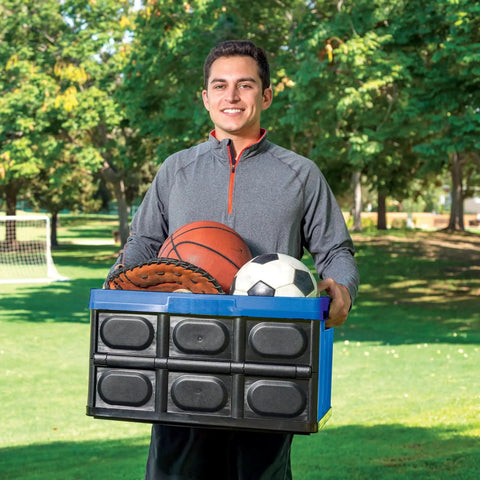 Heavy Duty Collapsible Storage Bin With 12 Gallon Capacity And Built In File Organizer Rails For Home Office Garage Car Trunk Folding Plastic Tote With Easy Grip Handles Black Blue carrying sports equipment in a park.