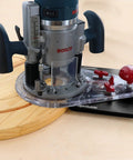 Edge And Mortise Router Guide For Straight And Curved Edges Universal Fit For Plunge And Fixed Base Routers Built In Mortise Guide All In One Large Surface For Radial Cuts Includes Two Non Marring Mortising Pins And Bonus Offset Base attached to a power router on a wooden board.