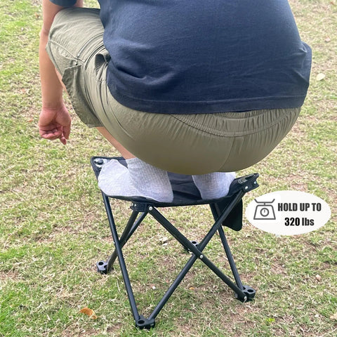 Person sitting on 2 Pack 13 Inch Portable Folding Camping Stool with Carry Bag, demonstrating weight capacity of 320 lbs on grass.