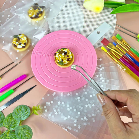 Premium Top Shelf 67 Piece Cookie Decorating Kit With Smooth Turntable Pro Brushes Scribe Needles Non Slip Pads Fresh Piping Bags For Totally Sick Cake Artists on pink turntable, cookie decorated with toppings.