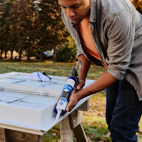 Person applying All Purpose Silicone Caulk Clear 10 Fl Oz Cartridge 12 Pack 100 Percent Waterproof Sealant With Tougher Adhesion Freeze And Sun Proof For Interior And Exterior Use to a white door outdoors.