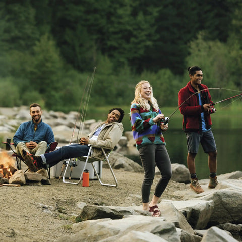 Four people fishing by a lakeside, using the MicroFine Dial-Adjustable Drag Spincast Fishing Reel with Dope Bite Alert.