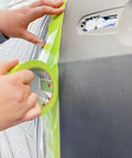 Person using Pro Grade Performance Masking Tape 233 Plus, 24 mm Wide by 55 m Long, on car for auto body painting.