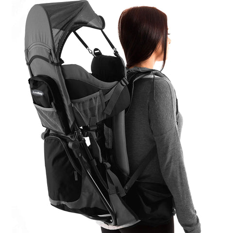 Outdoor hiking baby carrier backpack with sun hood, padded seat, and adjustable straps on woman, side view.