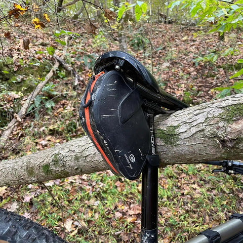 Waterproof Bike Seat Bag With TPU Welded Triangle Frame And YKK Zipper in a forest setting attached to a bike saddle.