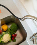 RV Ready Pull Down Kitchen Faucet With One Hand Lever in action, rinsing vegetables with detachable spray head in brushed satin nickel