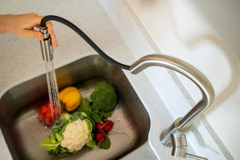 RV Ready Pull Down Kitchen Faucet With One Hand Lever in action, rinsing vegetables with detachable spray head in brushed satin nickel