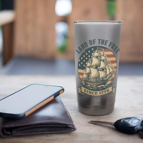 Patriotic Sailboat Stainless Steel Insulated Tumbler For Cold And Hot Beverages Red White And Blue Fourth Of July Gear For Independence Day Perfect Gift For Beach Or Boat Day And American Pride on table with phone and wallet