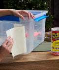 Applying Heavy Duty Rubberized Waterproof Tape That Seals Leaks And Patches It All For Indoor And Outdoor Use White 8 Inch By 5 Foot Pack Of 2 Tough As Nails Patch Job For Home RV Roofs Plumbing And Pool Repairs on a plastic container.