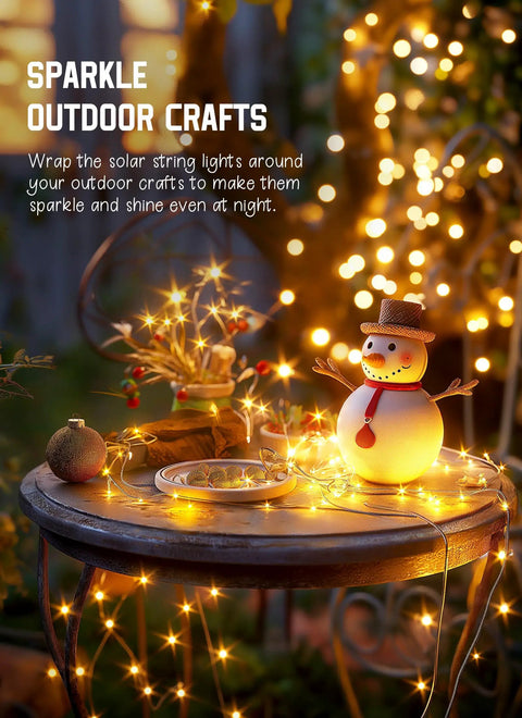 Solar Fairy Lights Outdoor 33 Ft 100 LED Warm White String Lights IP65 Waterproof on patio table with decorative snowman