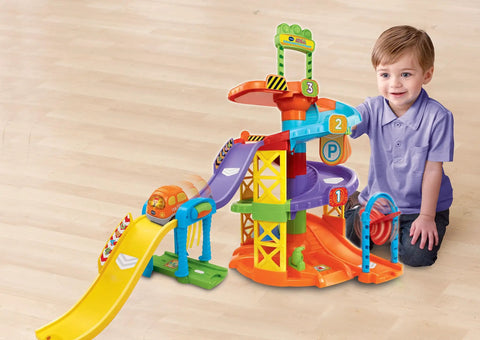 Child playing with Go Go Smart Wheels Spinning Spiral Tower Playset With Frustration Free Packaging For Kids Build Tracks Across Two Courses And Four Levels Featuring A Gas Station And Car Wash An Interactive Educational Vehicle Toy.