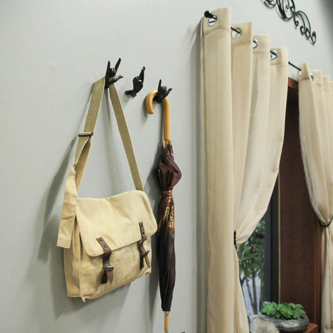 Set Of 3 Hand Gesture Wall Hooks holding a beige bag and umbrella, rustic cast iron decor for entryway, 4 inch design.