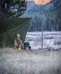 Camper under Supertarp Tarp Shelter In Pencott Wildwood Camo, Waterproof Ripstop Overland Camping Gear For Serious Weather