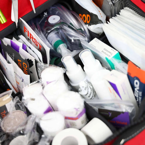 Close-up of Large EMT Trauma Kit For First Responders, fully stocked with supplies for CPR, airway, bleeding, wounds in red bag.