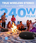 Outdoor beach party with Monster Bass 120W Outdoor Bluetooth Speaker Boombox, surrounded by people near a campfire, at sunset.