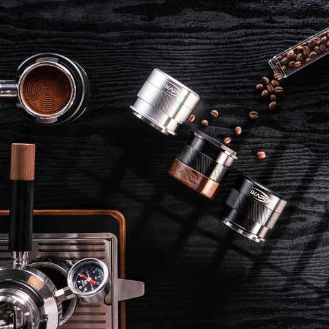 53mm Espresso Tamper For Barista Pros Premium Calibrated Spring Loaded Stainless Steel next to coffee beans and espresso machine