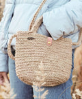 Person holding a handmade woven bag with a leather snap closure, suitable for use with Colorful 15 Piece Leather Snap Buckles Set For Purses And Bags.