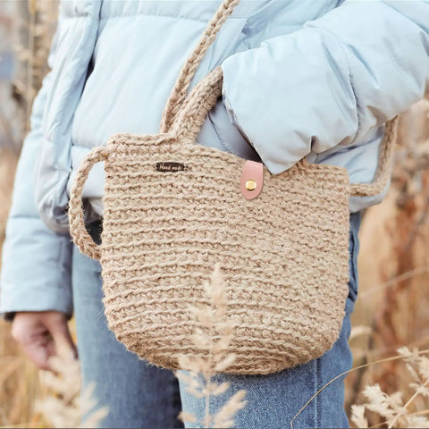 Person holding a handmade woven bag with a leather snap closure, suitable for use with Colorful 15 Piece Leather Snap Buckles Set For Purses And Bags.