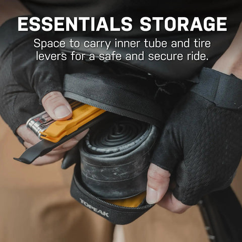 Hands holding Elementa Seatbag M Under-Saddle Bike Bag 0.5 Liter with inner tube and tire levers visible inside, detail view.