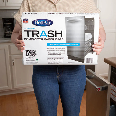 Person holding a box of Heavy Duty Trash Bags For Rectangular Canisters That Can Handle It All 16 Inch Deep 9 Inch Wide 17 Inch High Pack Of 24 Wet Strength Paper Liner With Reinforced Bottom Seal Pre Cuffed Made In USA in a kitchen.