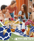 Group enjoying meal on table with Elastic Fitted Picnic Table Cover For 6 Foot Tables Waterproof Wipeable Vinyl With Flannel Back Navy 30x72 Inches Indoor Outdoor Table Protector Windproof Secure Fit And Easy Clean, navy pattern visible.