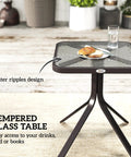 Three Piece Outdoor Glider Bistro Set With Glass Tabletop featuring water ripples design, glass with plate and glassware on a table.