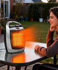 Woman enjoying Portable Space Heater And Fan For Office And Pets 2 In 1 Heat High 1500W And Low 750W, outdoor setting.