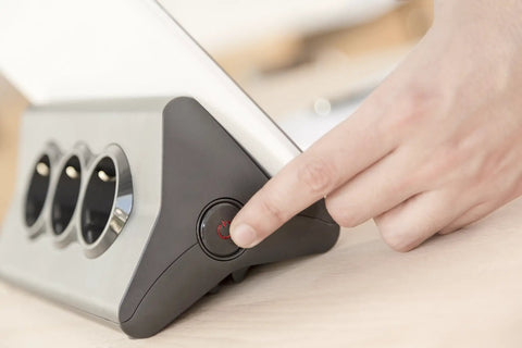 Kickstart Your Workspace Game With This Solid Three Outlet Power Strip And Dual Usb Charging Station features a hand pressing the on/off switch.
