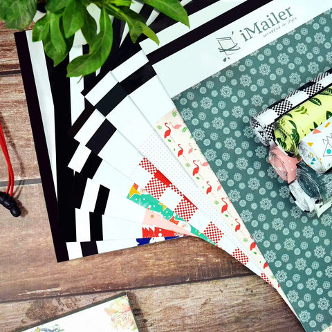 Assorted colorful poly mailers and thank you designs on a wooden table, showing variety in iMailer collection.